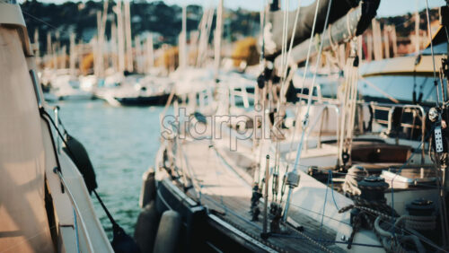 Video - Close view of yachts and sailboats docked side by side in a scenic marina during golden hour