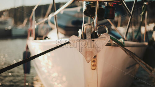 Video - Close up of a metal anchor on the bow of a sailboat reflecting golden sunlight