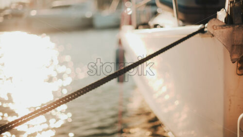 Video - Golden sunlight shimmering on the side of a yacht floating on calm water