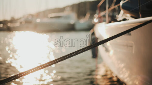 Video - Golden sunlight shimmering on the side of a yacht floating on calm water