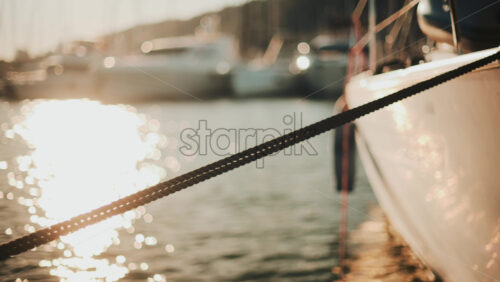 Video - Golden sunlight shimmering on the side of a yacht floating on calm water