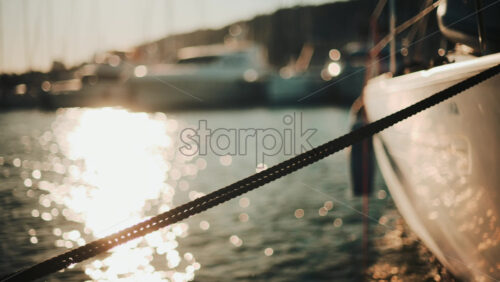 Video - Golden sunlight shimmering on the side of a yacht floating on calm water