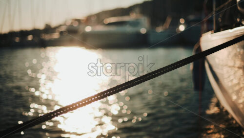 Video - Golden sunlight shimmering on the side of a yacht floating on calm water