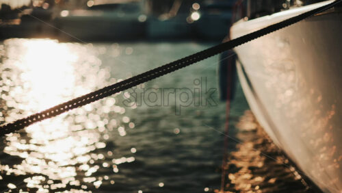Video - Golden sunlight shimmering on the side of a yacht floating on calm water