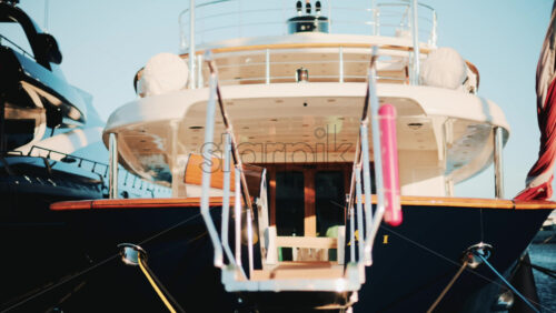 Video - Low angle close up of a yacht gangway leading onboard, with polished chrome handrails and soft golden light