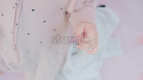 Video - Close up of baby's tiny hand reaching out gently in soft pastel tones
