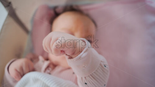 Video - Close up of baby's tiny hand reaching out gently in soft pastel tones