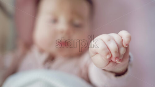 Video - Close up of baby's tiny hand reaching out gently in soft pastel tones