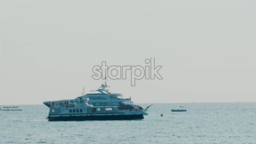 Video - Large cruise ship and luxury yachts anchored on calm blue sea under hazy sky