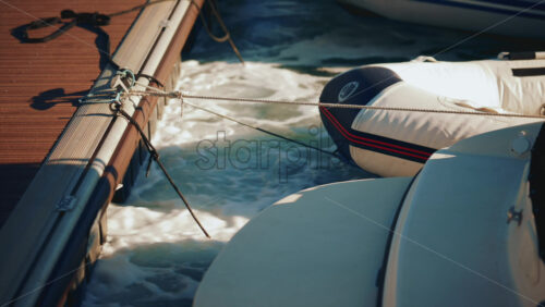 Video - Close up of ropes tied to a wooden dock as water splashes below