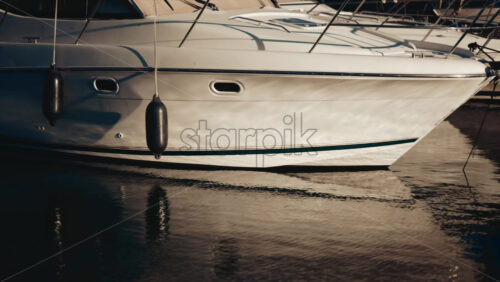 Video - Close up of a white yacht reflecting sunlight on calm water