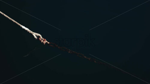 Video - Close up of an aged rope tied to the dock, floating on dark blue sea