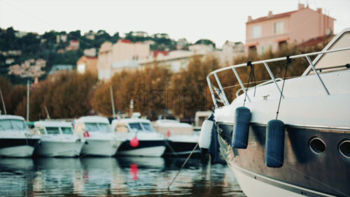 Video - Elegant sailboats lined up in a marina during golden hour, calm water reflecting the evening sun