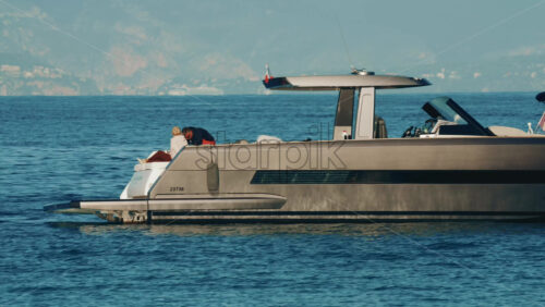 Video - Cannes, France - October 16, 2025: Elegant couple sitting together on the deck of a luxury yacht floating on calm blue sea