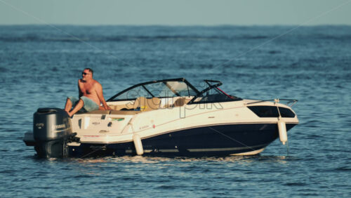 Video - Cannes, France - October 16, 2025: Man lying shirtless on a motorboat floating on calm blue water under sunlight
