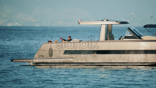 Video - Cannes, France - October 16, 2025: Side view of a sleek metallic yacht reflecting sunlight on calm blue water