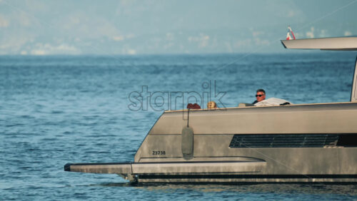Video - Cannes, France - October 16, 2025: Side view of a sleek metallic yacht reflecting sunlight on calm blue water