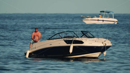 Video - Cannes, France - October 16, 2025: Man lying shirtless on a motorboat floating on calm blue water under sunlight