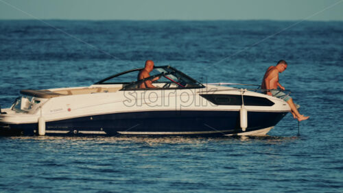 Video - Cannes, France - October 16, 2025: Man lying shirtless on a motorboat floating on calm blue water under sunlight