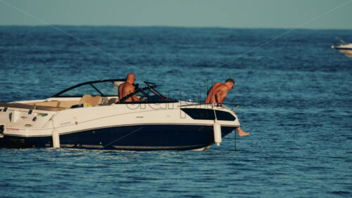 Video - Cannes, France - October 16, 2025: Man lying shirtless on a motorboat floating on calm blue water under sunlight