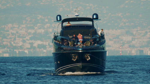 Video - Cannes, France - October 16, 2025: Elegant black yacht sailing across calm sea with a scenic coastal city backdrop