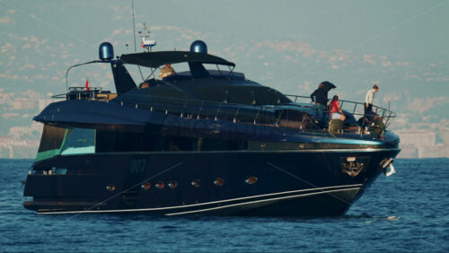 Video - Cannes, France - October 16, 2025: Elegant black yacht sailing across calm sea with a scenic coastal city backdrop