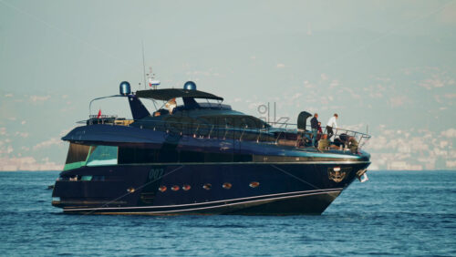 Video - Cannes, France - October 16, 2025: Elegant black yacht sailing across calm sea with a scenic coastal city backdrop