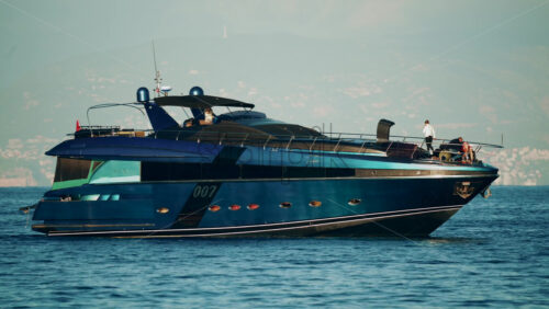 Video - Cannes, France - October 16, 2025: Elegant black yacht sailing across calm sea with a scenic coastal city backdrop