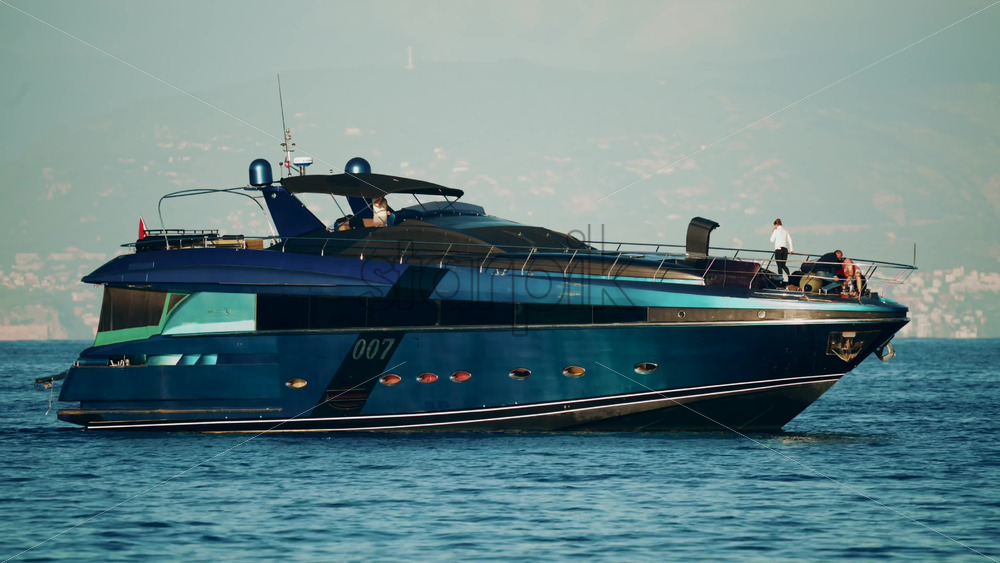 Video - Cannes, France - October 16, 2025: Elegant black yacht sailing across calm sea with a scenic coastal city backdrop