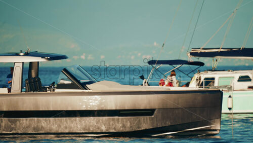 Video - Side view of a sleek metallic yacht reflecting sunlight on calm blue water