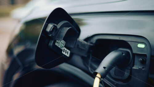 Video - Electric vehicle plugged into charging port in daylight