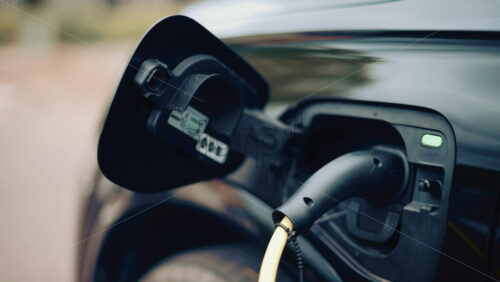 Video - Electric vehicle plugged into charging port in daylight