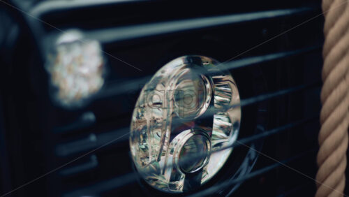 Video - Close up of a luxury car headlight with soft reflections and a rope beside it