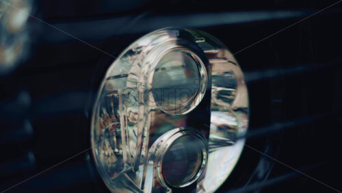 Video - Close up of a luxury car headlight with soft reflections and a rope beside it