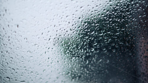 Video - Close up of raindrops on a glass window with soft bokeh background