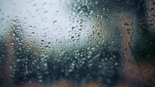 Video - Close up of raindrops on a glass window with soft bokeh background