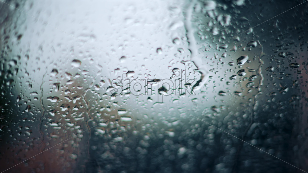 Video - Close up of raindrops on a glass window with soft bokeh background