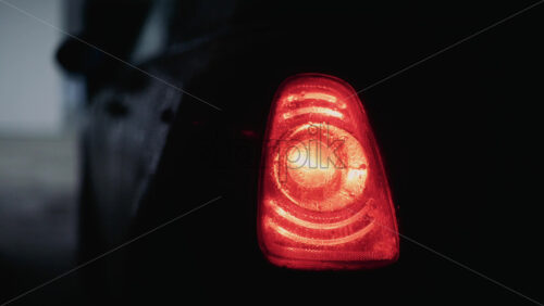 Video - Close up shot of a glowing red car taillight covered in raindrops at night