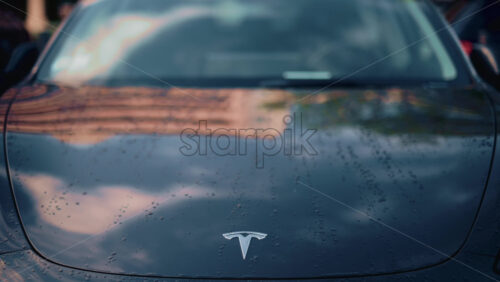 Video - Cannes, France - October 16, 2025: Close up of a black Tesla Model 3 hood glistening with water droplets after the rain