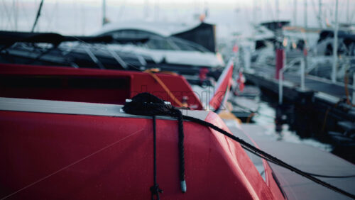 Video - Close up of a red boat moored at a marina, with black rope coiled neatly on the deck