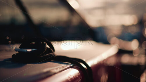 Video - Close up of a boat deck during sunset, with a focus on a black rope coiled on the surface