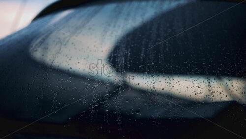 Video - Close up of raindrops on a glass window, softly illuminated by blurred bokeh lights in the background