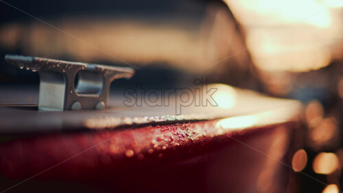 Video - Close up of a boat cleat on a red hull, shining under warm evening sunlight