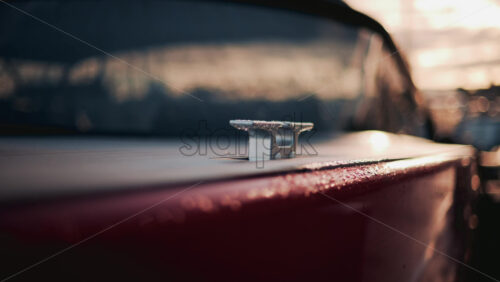 Video - Close up of a boat cleat on a red hull, shining under warm evening sunlight