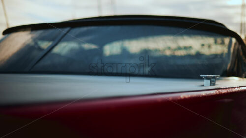Video - Close up of a boat cleat on a red hull, shining under warm evening sunlight