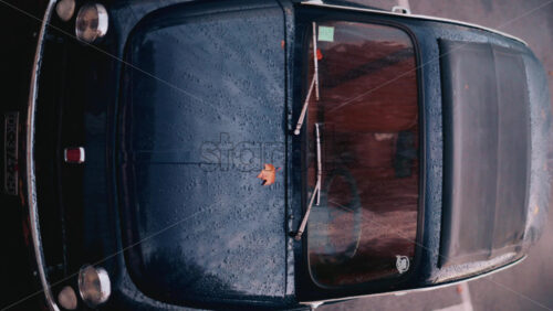 Video - Cannes, France - October 20, 2025: Aerial view of a classic blue car covered in raindrops, parked in an urban lot. Vertical