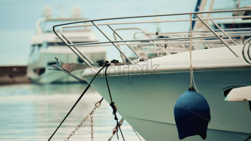 Video - Detailed close up of a yacht's bow and anchor tied with ropes, with other boats blurred in the background