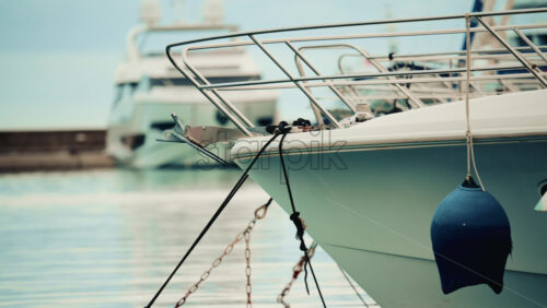 Video - Detailed close up of a yacht's bow and anchor tied with ropes, with other boats blurred in the background
