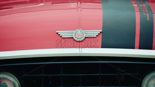 Video - Cannes, France - October 20, 2025: Frontal view of a vintage red Mini Cooper with black stripes, parked in front of a textured wall
