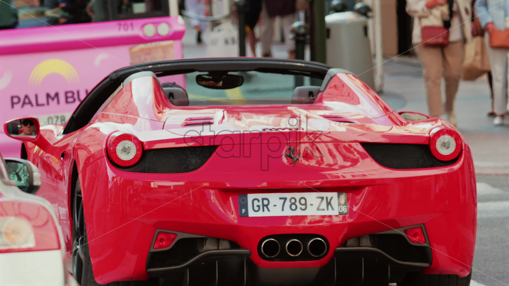 Video - Cannes, France - October 4, 2025: Rear view of a red convertible Ferrari car driving through a city street